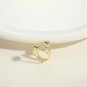 Detail shot of a double-ball spiral ring with a polished gold finish on a white plate