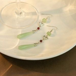Detail of light green jade teardrop earrings with silver accents on a white plate
