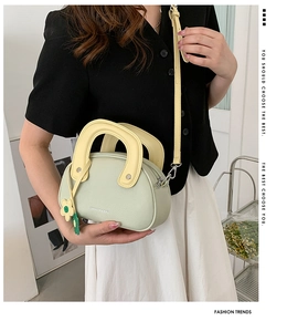 Détail du sac en cuir vert clair avec poignée jaune et pendentif en forme de marguerite