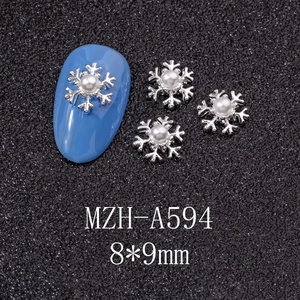 Macro detail of silver snowflake nail charms with white pearls on blue manicured nails