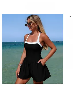Detail of a black and white contrast skirt-style swimsuit worn by a model at the beach