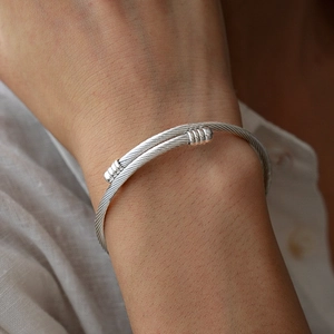 Detail of silver twisted cable cuff bracelet with polished ends on linen sleeve