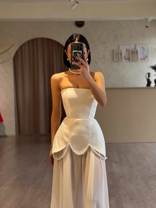 Detail of elegant white satin maxi dress featuring a pearl waist detail and flowing skirt