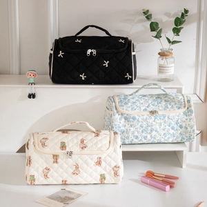 Three quilted cotton travel makeup bags with floral and embroidery patterns and handles