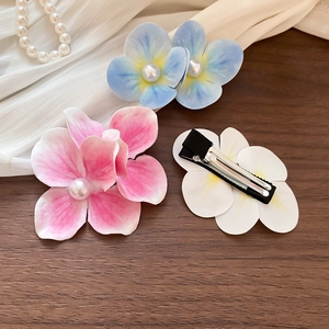 Close-up of floral hair clips with pearls in blue, pink, and white on silk petals