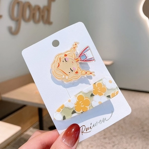 Detailed view of cute cartoon girl and floral resin hair clips on a white display card