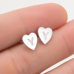 Gros plan de boucles d'oreilles cœur en argent avec gravure de la lettre Y