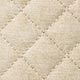 Macro shot of beige diamond quilted leather texture and fine stitching on tote bag