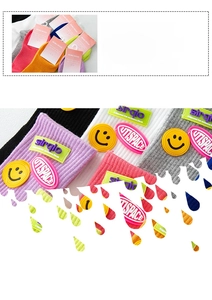 Close-up of knit cotton socks featuring a yellow smiley face patch and high-quality logo tag