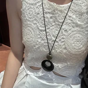 Close-up detail of retro ethnic resin ring pendant necklace worn on a white lace top