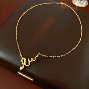 Macro shot of gold-plated snake pendant with scales and white gemstone on fine O-chain