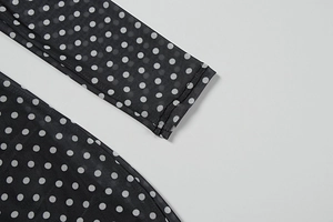 Close-up of semi-transparent black mesh fabric with white polka dots and neat cuff stitching