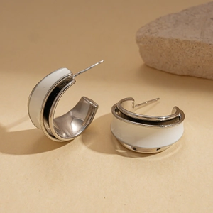 Detail of silver C-shaped double hoop earrings with white enamel finish on stone