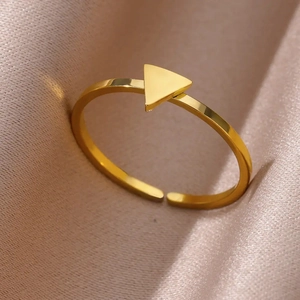 Detailed side view of a gold triangle ring placed on luxury champagne satin fabric