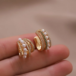 Gold star ear cuffs featuring white pearls and green stones in an asymmetric design