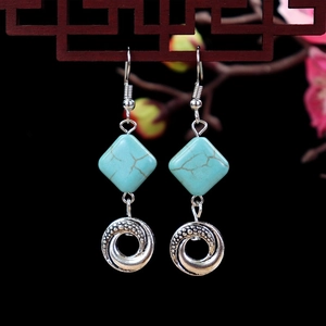 Detailed macro of vintage turquoise drop earrings with floral engraved silver charms