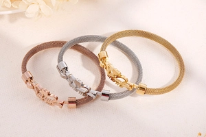 Detailed view of MOM lettering on scorpion buckle of mesh heart bracelets in three colors