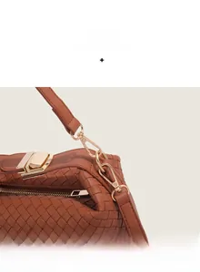 Detail of dark brown woven leather handbag showing gold hardware and top zipper closure