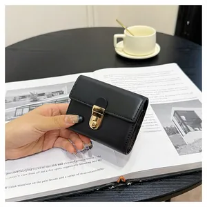 Close-up of a compact black leather wallet featuring a stylish gold oval twist-lock closure
