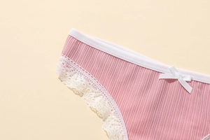Gros plan détaillé du slip côtelé rose avec bordure en dentelle blanche et petit nœud
