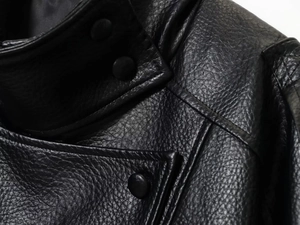 Detail van de opstaande kraag en matte knopen op een zwart kunstleren jasje met dubbele stiksels