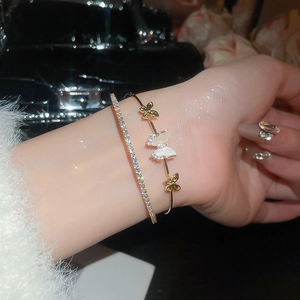 Detail of layered gold zircon butterfly bangle and sparkling diamond bracelet for women