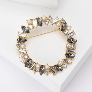 Macro view of crystal wreath brooch with grey stones and white pearls on gold base
