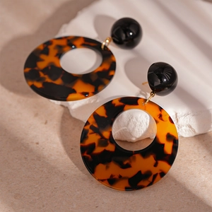 Detail view of retro leopard print resin hoop earrings on a textured stone display