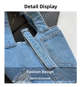 Detailed macro view of light blue denim fabric with orange stitching and metal hardware