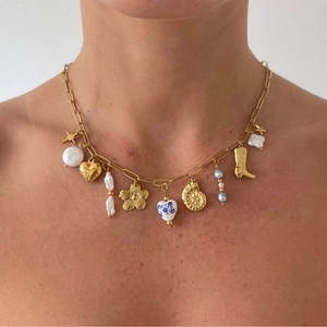 Gold charm necklace with baroque pearls, stars, and ceramic hearts on a female model