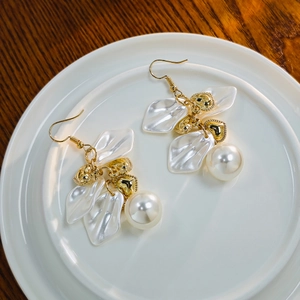 Detail of vintage French style earrings with pearl petals and golden heart pendants
