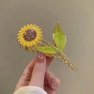 Detail of sunflower hair claw clip with yellow petals, green leaves and crystal center