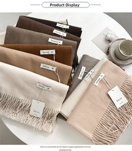Close-up of stacked cashmere-feel earth-tone scarves featuring fine tassel details and tags