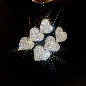 Close-up of heart-shaped rhinestone earrings with sparkling silver tassels in a macro view