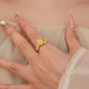 Close-up of golden matte oval ring with embossed circular patterns on a person's finger