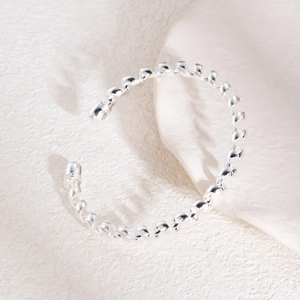 Gros plan d'un bracelet en métal argenté à spirales avec un design torsadé poli