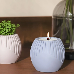 Close-up of a lit candle in a blue ribbed silicone mold jar with textured stripe details
