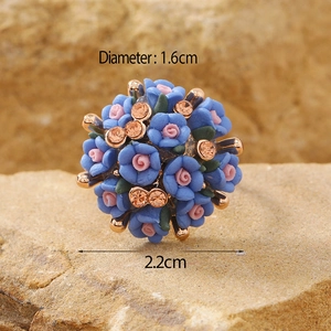 Macro detail of floral sphere earrings with blue and pink flowers and gold accents