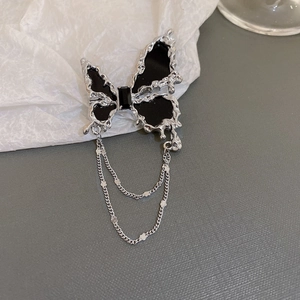 Macro view of vintage butterfly brooch with black resin inlay and silver tassel chain detail