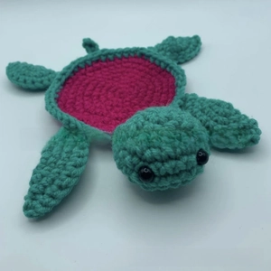 Detail of handmade crochet turtle coaster with green yarn and purple shell pattern