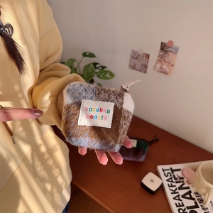 Detailed close-up of a mini plush checkered cosmetic bag held by a model in soft lighting