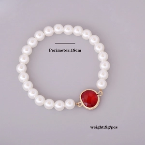 Detail of 18cm pearl bracelet with a faceted red heart pendant and gold metal accents