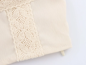 Macro shot of beige lace patchwork and zipper detail on a cropped camisole top