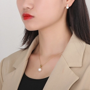 Gros plan d'un ensemble élégant collier en acier doré et boucles d'oreilles perles