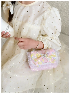 Detail of pink girls mini handbag featuring a sequined bow and elegant pearl handle