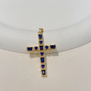 Detailed close-up of a gold-plated cross pendant featuring inlaid dark blue zircon stones