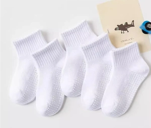 Detail of five pairs of white cotton mesh socks showing non-slip grip soles for children
