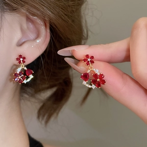 Close-up of 18k gold flower earrings featuring red gemstones and sparkling crystals
