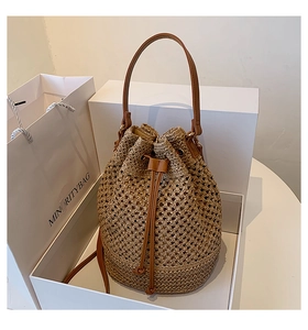 Straw bucket bag with brown leather straps displayed in a luxury white gift box