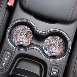 Close-up of two highland cow car coasters with colorful illustration in a cup holder